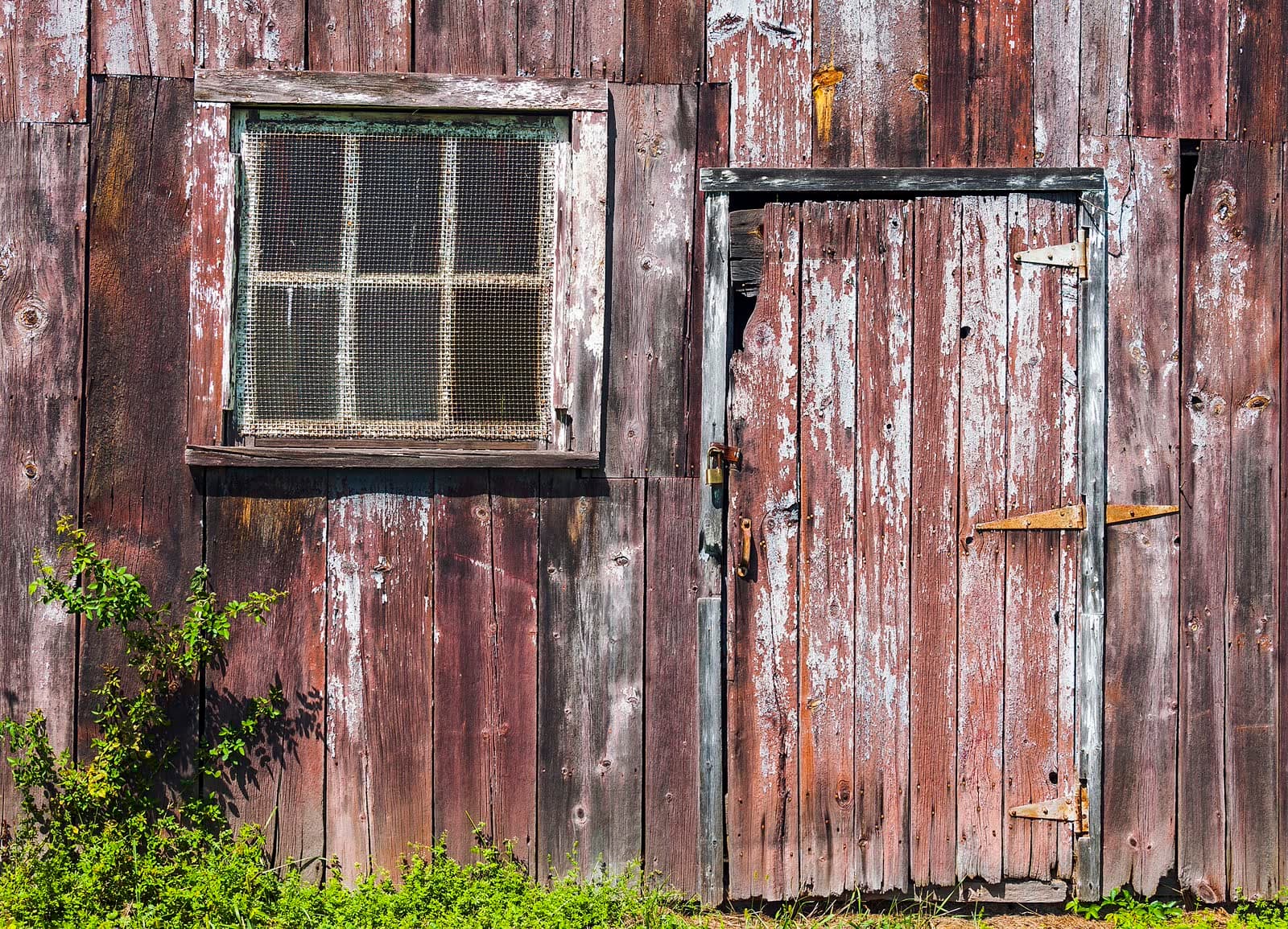 Weathered timber garage wall with a small side door and window