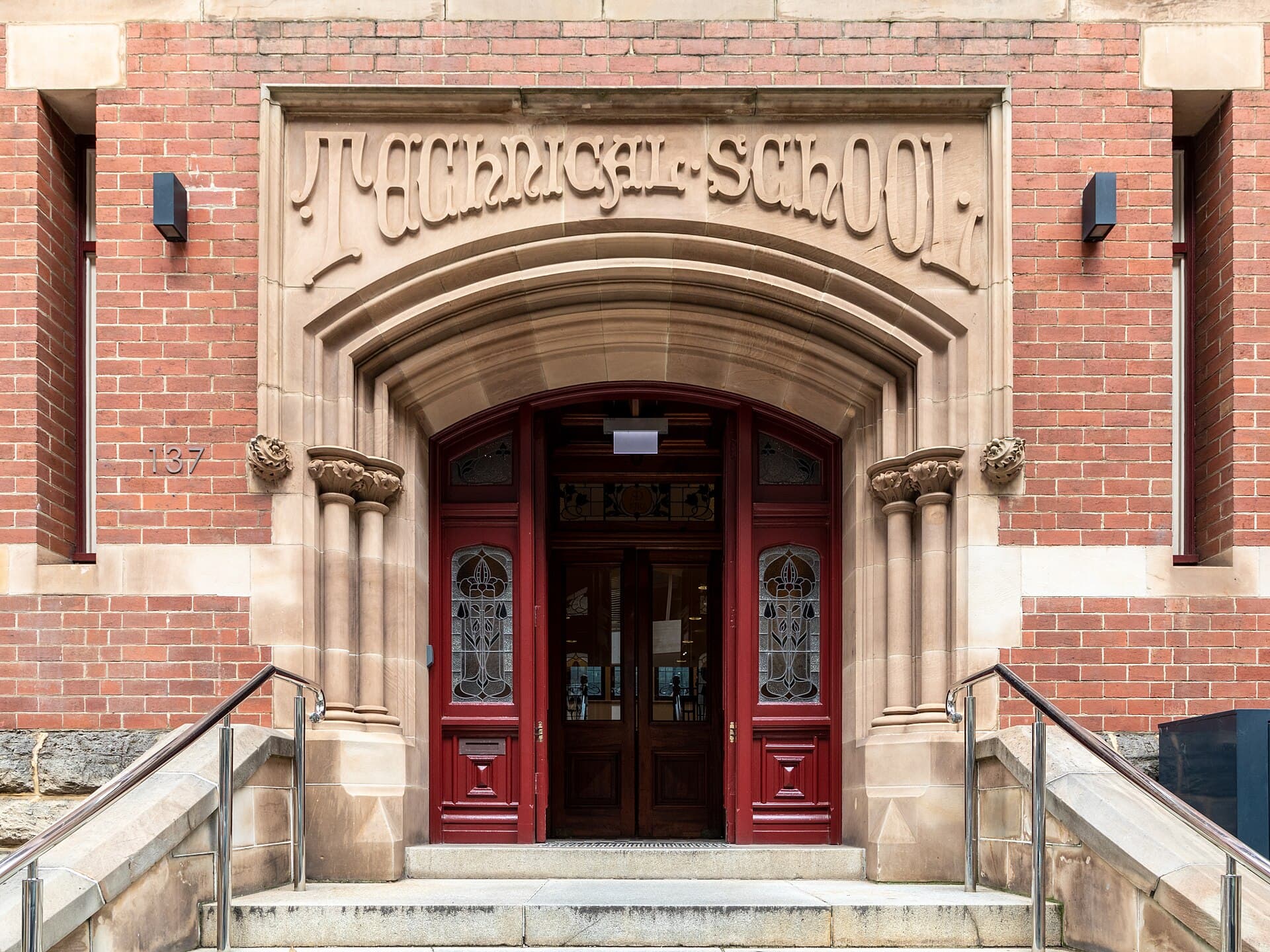 Brick and stone facade of the Old Perth Technical School with tall windows and entries